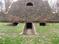 Die Nordseite der Pyramide mit hohlwegartigen Zugängen zum zentralen Kellergewölbe (Mitte) und zu zwei kleinen Kammern (Aufnahme 2009)